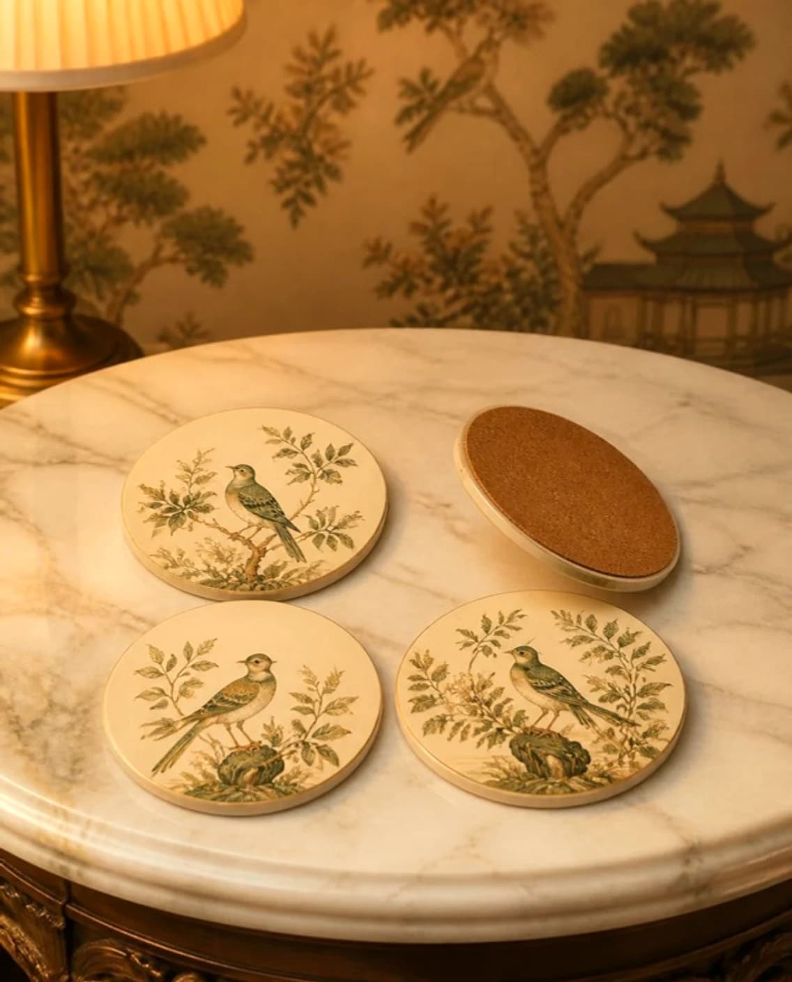 Round coasters printed with chinoiserie birds, one turned to show its cork back, on marble
