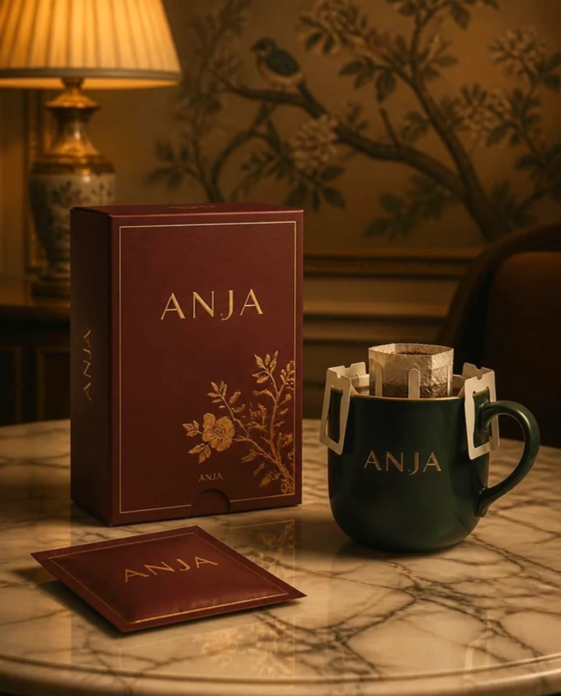 Oxblood box of coffee drip bags printed ANJA, one bag hooked over a green cup